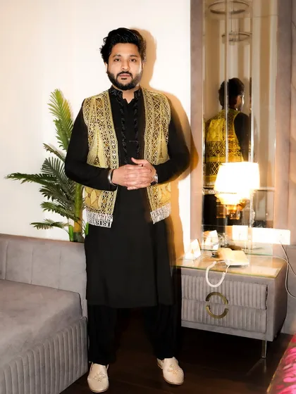 A full-length portrait in a classic black kurta with a stunning golden embroidered jacket. This is my go-to look for an elegant Sufi mehfil.