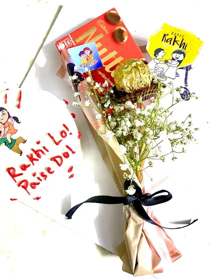 For the sibling who loves a bit of fun! This Rakhi combo features a bento cake with a playful "Rakhi Lo! Paise Do!" message and a matching chocolate bouquet.