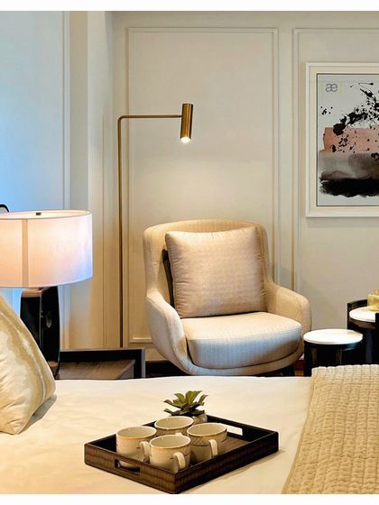 A cozy reading corner in the DLF apartment bedroom, complete with a comfortable armchair, side tables, and focused lighting. These small, thoughtful spaces are essential for creating a true sense of home.