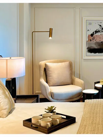 A cozy reading corner in the DLF apartment bedroom, complete with a comfortable armchair, side tables, and focused lighting. These small, thoughtful spaces are essential for creating a true sense of home.