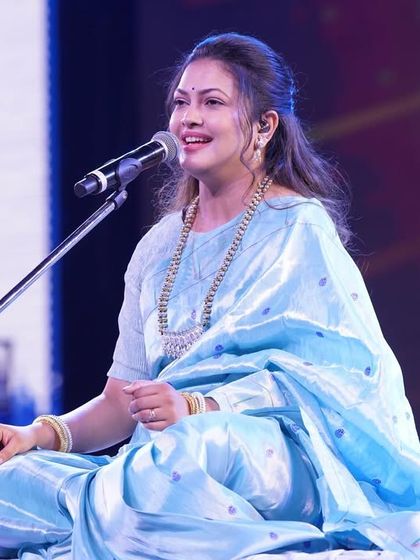 Priyanka Barve seated on stage, showcasing the full grace of the Paithani saree drape.