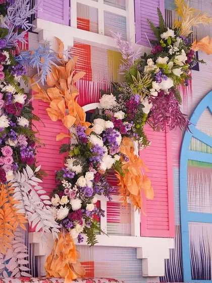 A detailed view of the floral decor on the colorful window panels. The mix of fresh flowers and dried orange foliage creates a rich texture and a vibrant color story.