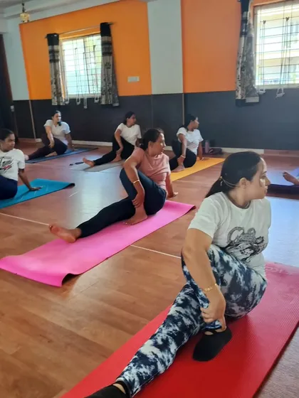 Students in a group class practicing a seated spinal twist. The shared focus and synchronized movement create a powerful collective energy in the studio.