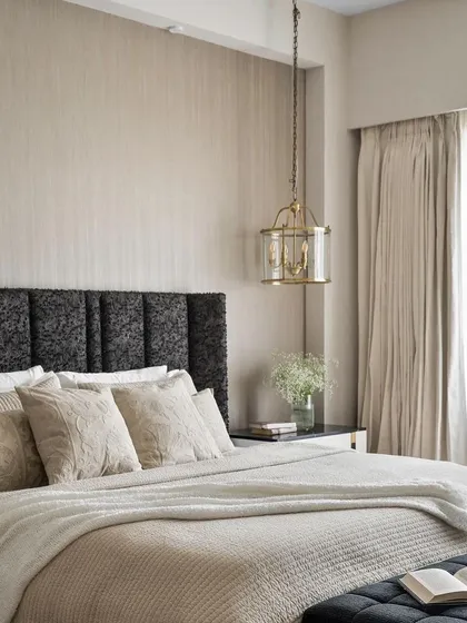 A serene bedroom from a Studio Sylus project in Architectural Digest, featuring our custom-made bed with a textured, panelled headboard in a dark, luxurious fabric.