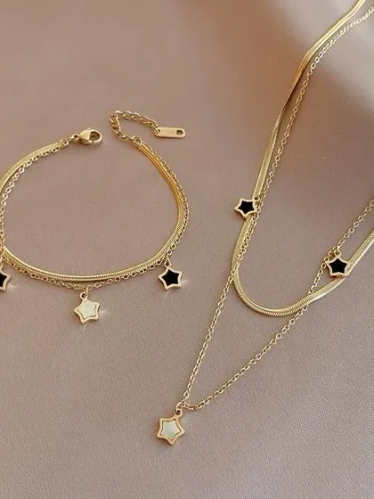 A matching set featuring a layered necklace and bracelet with a snake chain and dangling star charms in black and white enamel.