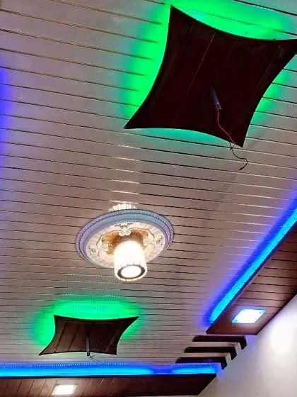 This creative PVC ceiling design features unique curved elements and a mix of green and blue lighting. It's a great example of how PVC can be used for more than just straight lines.