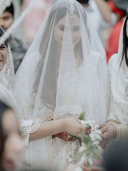 A beautiful moment from a Nikah ceremony, where the bride is surrounded by smiling family members. The all-white theme creates an atmosphere of serenity and purity.