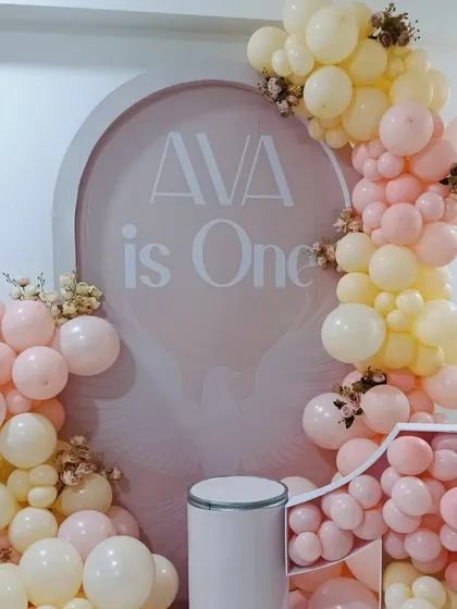 This elegant first birthday setup for Ava features a soft pink and cream color palette. The custom arched backdrop and organic balloon arrangement create a sophisticated and modern look.