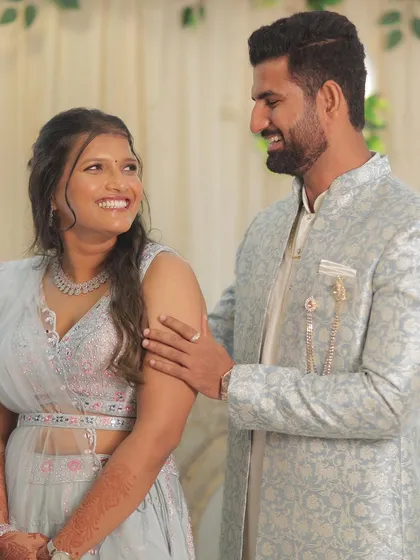 A sweet moment between the couple on their engagement day. The bride wears a soft glam look with a focus on bright, happy features that match her light blue pastel outfit.