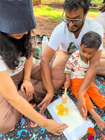 A beautiful family moment. Both parents are engaged as their child learns the technique of flower pounding, creating a shared memory through art.