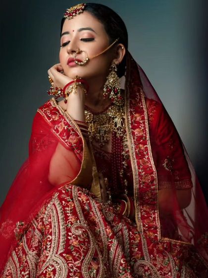 An artistic shot of a bride in a red lehenga, wearing a traditional red-beaded jewellery set.