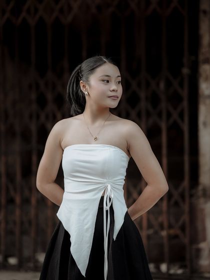 A simple, elegant portrait against a dark, industrial background. The contrast between the model's soft look and the hard environment creates a compelling image.