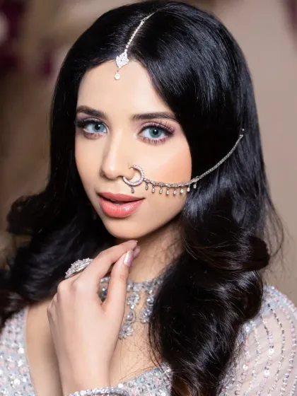 This student's work features a modern reception look with striking blue contact lenses and diamond jewelry. Learning to work with accessories is a key part of the course.