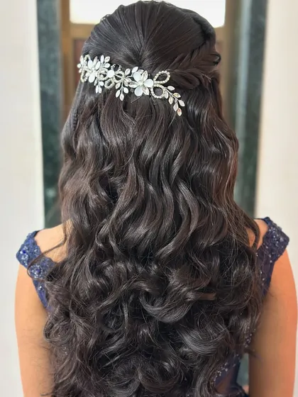 Another beautiful half-up hairstyle with voluminous curls and a floral crystal accessory, demonstrating a timeless and romantic look.