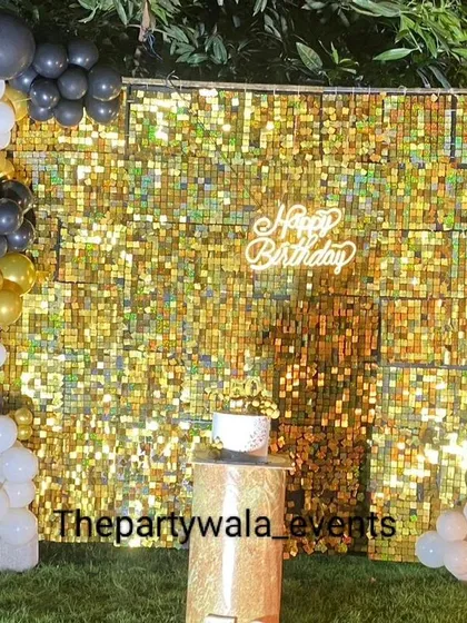 A glamorous 50th birthday celebration with a full gold sequin wall. The black, white, and gold balloon garland adds a touch of elegance to this milestone party.