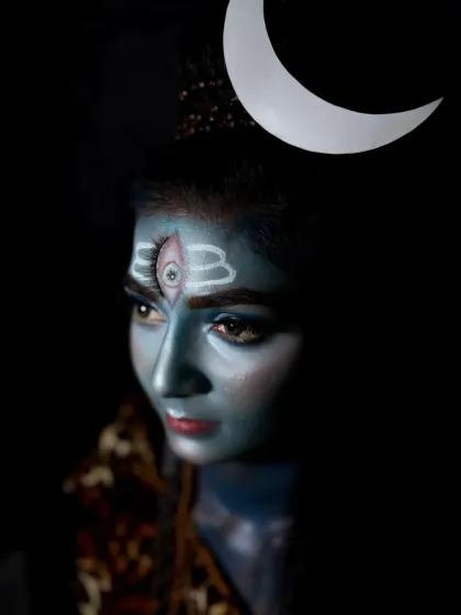 A close-up focusing on the eye makeup and the hand-painted third eye. The subtle shimmer on the lids adds a touch of glamour to the otherwise traditional depiction.