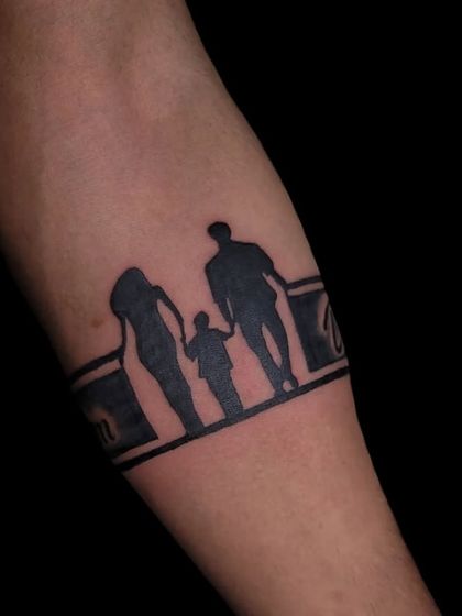 A family silhouette tattoo designed as an armband, showing a mother, father, and child.