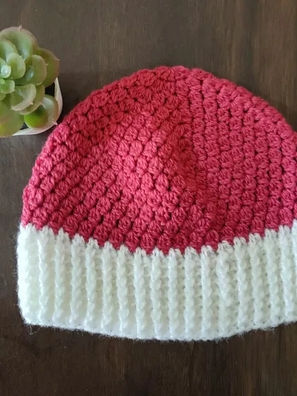 The 'Flora' beanie is a quick and easy project, perfect for using up leftover yarn. It features a simple cluster stitch for the body and a stretchy ribbed brim for a snug fit.