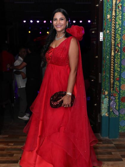 A smiling Payal in her custom red gown, a vision of elegance and happiness.