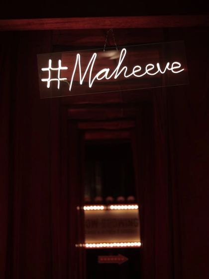 The couple's wedding hashtag, #Maheeve, in a stylish neon sign, hung in a hallway of red velvet drapes.