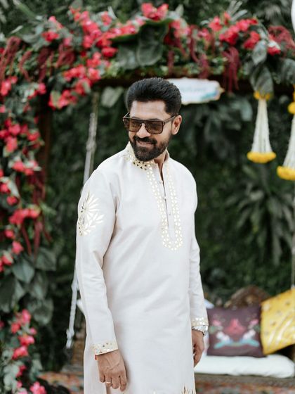 The groom looking dapper and relaxed before his Haldi ceremony, set against a beautiful floral arch. We style every corner for perfect pictures.