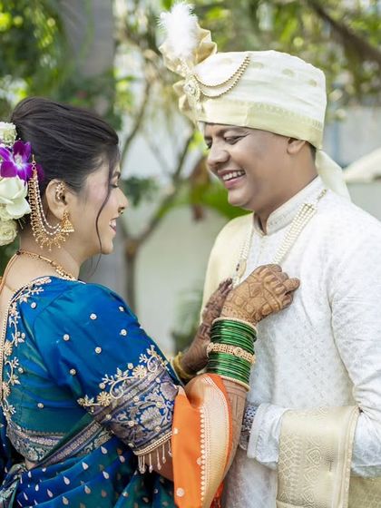A playful and candid moment, with the bride adjusting the groom's attire, full of smiles.