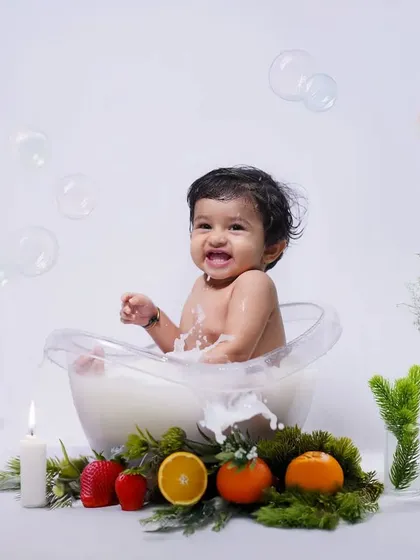 A minimalist milk bath session in the studio, decorated with candles and fresh fruits. This setup creates a clean, bright, and artistic portrait of your baby.