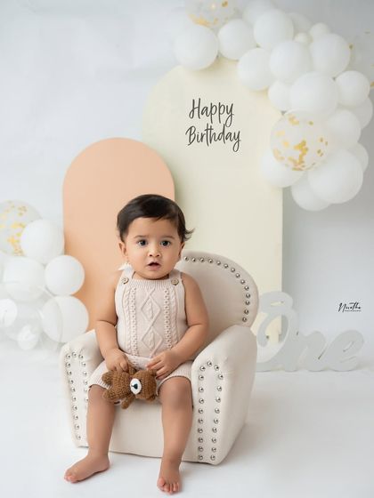 A first birthday portrait with a cute teddy bear prop.