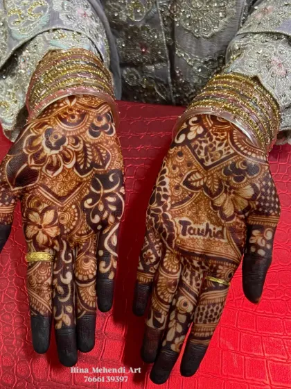 A close-up of the rich henna stain, highlighting the groom's name 'Tauhid' beautifully written on the bride's palm.