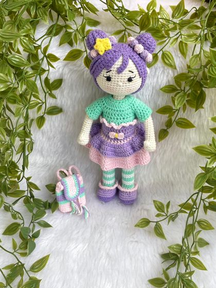 A beautiful doll with purple hair buns and a tutu dress. She also comes with a tiny backpack for her adventures. The striped stockings are attached, but her dress and shoes are removable.