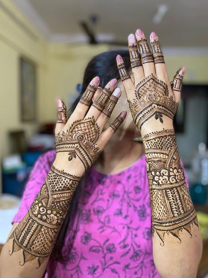 A shy bride pose, showing how the intricate mehendi on both hands comes together to create a stunning complete picture.