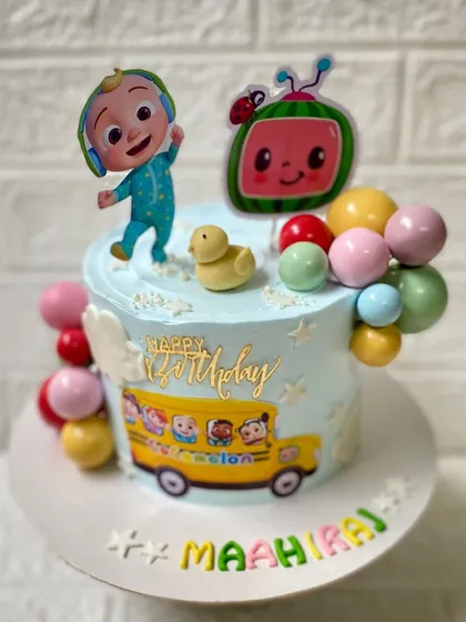 The wheels on the bus go round and round. A colourful Cocomelon-themed chocolate cake, complete with JJ, the iconic watermelon, and a school bus.