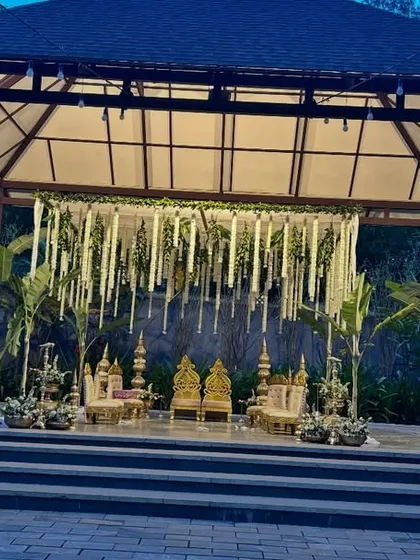 This is the same green and white mandap viewed in the evening. The strategic uplighting highlights the hanging tuberose garlands and the architectural details of the gazebo, creating a romantic and serene atmosphere for a night ceremony.