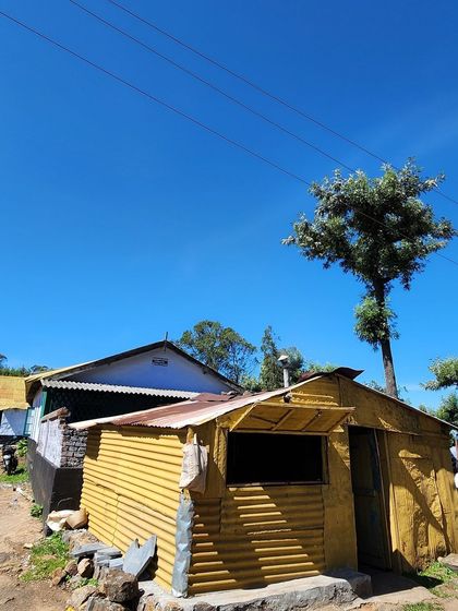 A rustic yellow hut against a brilliant blue sky, showcasing the simple and colorful life in the hills.