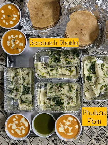 A meal of Sandwich Dhokla, Phulkas, and creamy Paneer Butter Masala.