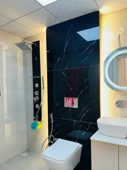 A black and white themed bathroom in a newly completed project at JM Florence, featuring a black marble shower wall and a shower panel system.