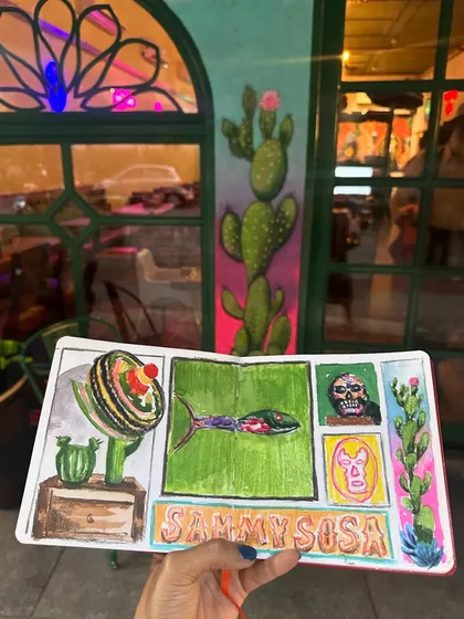 My sketchbook held up against a painted cactus, another element from the restaurant's decor that I incorporated into my collage.