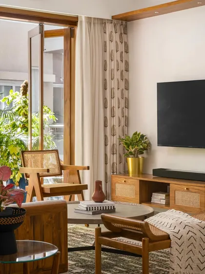 The 'Palaash' living room, featuring a custom wood and glass door that recreates a classic French door design, adding warmth and a connection to the balcony.