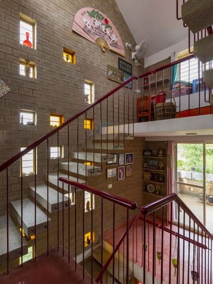 The staircase in the Verma's house is designed with small, illuminated niches built into the compressed earth block wall. This feature turns a simple stairway into a personal gallery for displaying small treasures and adds a warm, ambient glow.
