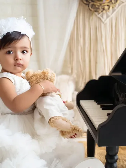 A quiet moment with a furry friend. This close-up from a sitter session highlights the beautiful, innocent expression of a baby girl holding her teddy bear.