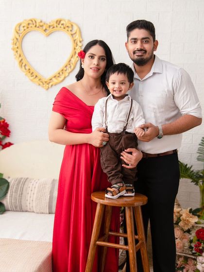 A classic family portrait with a touch of romance. The red dress and floral accents create a warm and loving atmosphere.