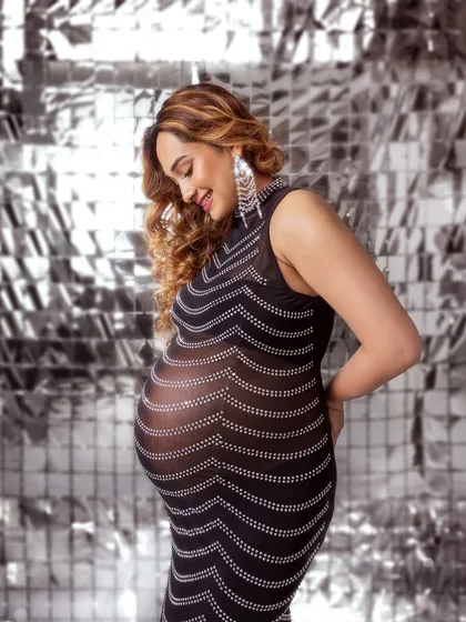 A glamorous solo shot in a sheer, sparkling dress against a silver disco backdrop. Fun, fashionable, and daring.
