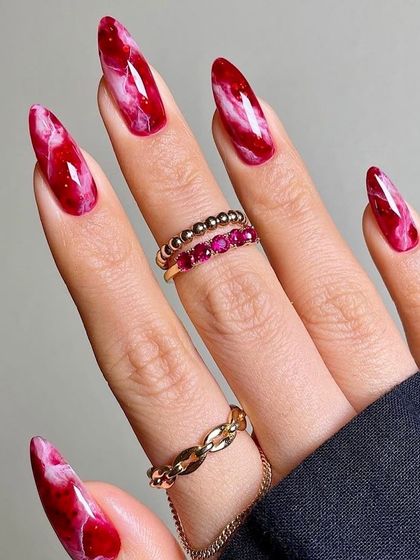A passionate and fiery look, these nails are designed to resemble red quartz or marble. The deep red and white swirls create a dramatic and powerful effect on these long, almond-shaped nails.