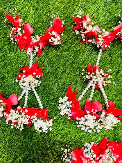 A closer look at the hath phool from the red floral baby shower set. The design uses red petals and baby's breath for a festive feel.