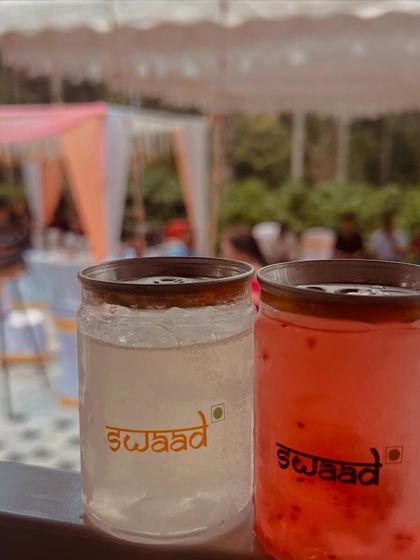 A pair of refreshing mocktails served in my branded jars, with the event setup in the background. These are perfect for welcoming guests to a wedding or corporate function.