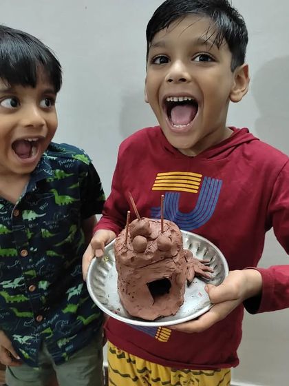 The pure excitement of creating something new! These brothers are thrilled with their finished clay monster, a perfect example of how art activities can be a fun and bonding experience.