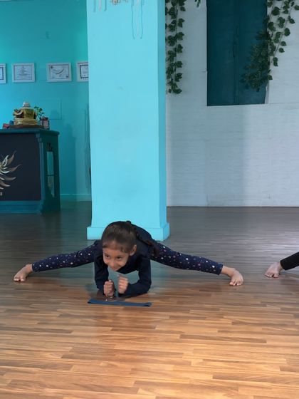 Holding a perfect center split. The focus and determination on this young student's face show that she is learning the discipline required to excel.