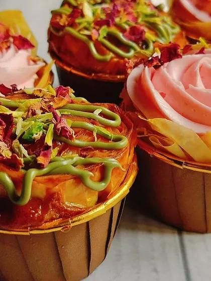 A close-up shot that captures the rich textures of the Baklava cupcake, from the flaky pastry to the creamy buttercream and crunchy pistachio garnish.