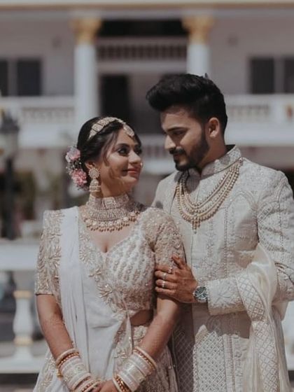 Two hearts, one soul. The bride and groom look like a royal couple in their coordinated white and gold outfits.