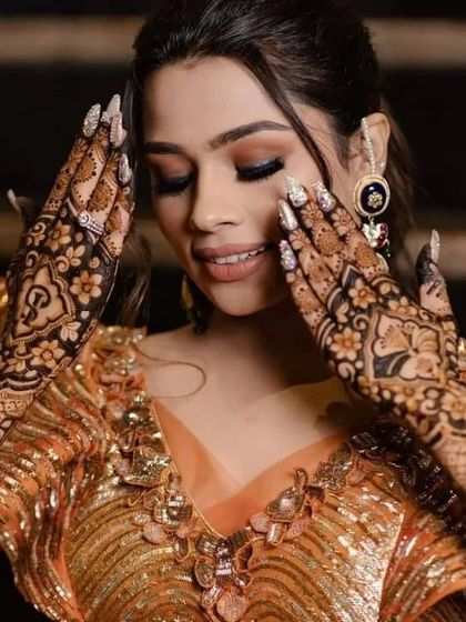 A close-up of a gorgeous bride, her hands framing her face to show off the detailed mehndi work.